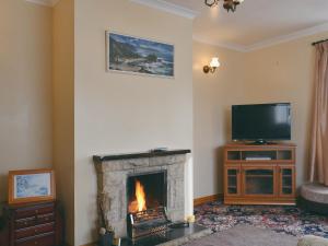 a living room with a fireplace and a flat screen tv at Shore View in Portree