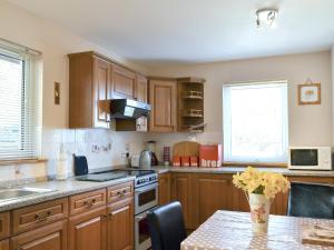 a kitchen with wooden cabinets and a table with flowers at Shore View in Portree