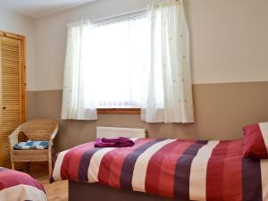 a bedroom with a bed with a striped blanket and a window at Shore View in Portree