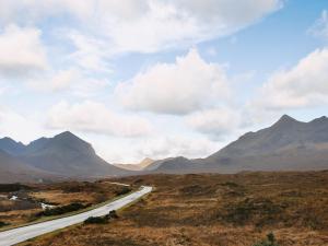 a road in a field with mountains in the background at Shore View in Portree