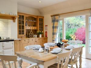 een keuken met een houten tafel en witte stoelen bij Dalbeathie Cottage in Birnam