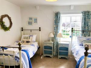 a bedroom with two beds and a window at Laurel Cottage in Stoke Gabriel