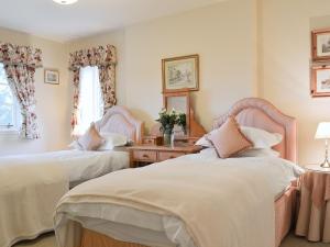 a bedroom with two beds and a table with flowers at Dalbeathie Cottage in Birnam