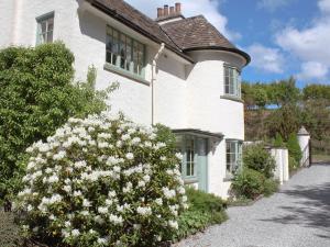 a white house with a flowering bush in front of it at Dalbeathie Cottage in Birnam