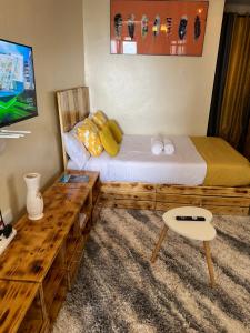 1 dormitorio con 2 camas, mesa y TV en Ruby Modern Homes Studio-Imara Daima,Behind Imaara Mall-JKIA-Horizon en Nairobi