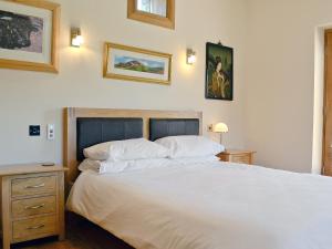 LlanfrothenにあるBwthyn Llwynog - HW7739のベッドルーム1室(大きな白いベッド1台付)が備わります。壁に2枚の絵が飾られています。