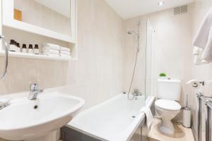 Baño blanco con lavabo y aseo en Urban Hyde Park One-Bedroom Retreat, en Londres