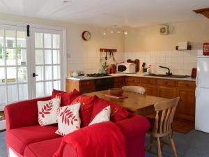a living room with a red couch and a kitchen at Felbridge Cottage in Bardon Mill