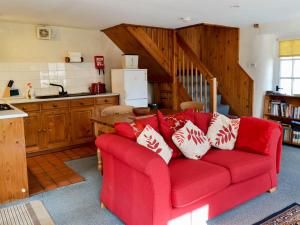a living room with a red couch in a kitchen at Felbridge Cottage in Bardon Mill