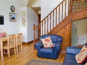 a living room with a blue leather chair and stairs at Jasmine Cottage - 30503 in West Firle