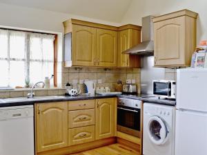 a kitchen with wooden cabinets and a washer and dryer at Jasmine Cottage - 30503 in West Firle