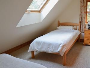 a attic bedroom with a bed and a window at Jasmine Cottage - 30503 in West Firle