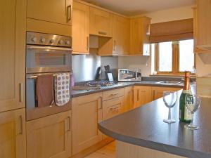 a kitchen with wooden cabinets and a counter with wine glasses at Stables - 24734 in Bearsted