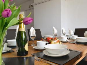 a wooden table with white dishes and a vase with purple flowers at Beacon Cottage in Ivybridge