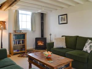 a living room with a green couch and a fireplace at Orchard Chapel in Much Marcle