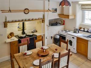 a kitchen with a wooden table with chairs and a stove at Crogen Wing in Llandrillo