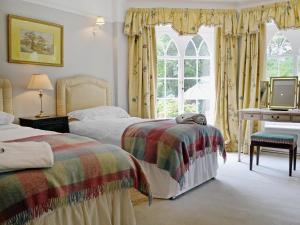 a bedroom with two beds and a desk and a piano at Crogen Wing in Llandrillo