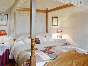 a bedroom with a canopy bed with two tables at Rose Cottage - Lpd in Ireby
