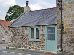 an old stone cottage with a blue door at No2 The Neuk in Belford