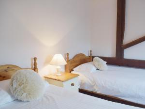 a bedroom with two beds and a table with a lamp at Coriander - E4323 in Ludham