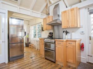 cocina con armarios de madera y nevera de acero inoxidable en The Boathouse, en Dartmouth