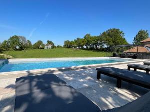 duży basen z dwoma ławkami obok niego w obiekcie La Millière - Chambres d'hôtes - Piscine & campagne - Marie-Anne & Marie-Adélaïde w mieście Le Poiré-sur-Vie