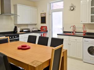 a kitchen with a wooden table with chairs and a sink at Chapel View in Filey