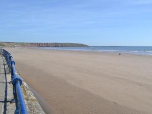 a beach with a blue fence and the ocean at Chapel View in Filey