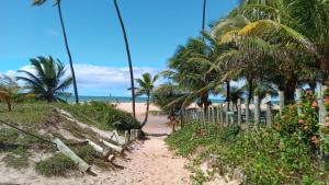 um caminho para a praia com palmeiras em Casa agradável em condomínio perto da praia. em Mata de São João