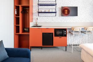 uma cozinha com um armário laranja e uma televisão em Boutique Hotel Mezi švy em Hradec Králové