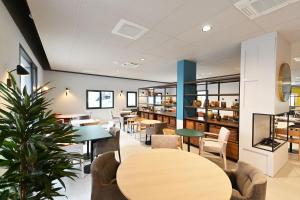 un restaurant avec des tables, des chaises et une plante dans l'établissement Résidence Services CAZAM, à Clermont-Ferrand