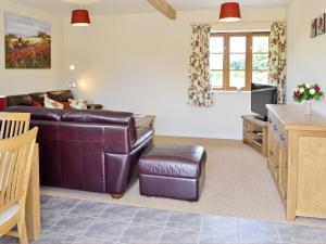 a living room with a leather couch and a tv at Woodlanders - 29954 in Wootton Glanville