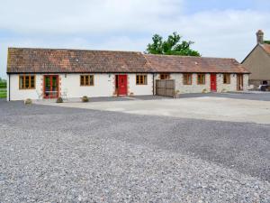 a white building with red doors and a driveway at Woodlanders - 29954 in Wootton Glanville