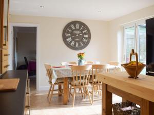 a dining room with a table and a clock on the wall at Meadow View in Harley