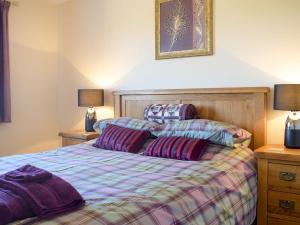 a bedroom with a bed with purple sheets and two lamps at Meadow View in Harley