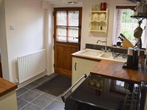 a kitchen with a sink and a stove top oven at Farm Cottage in Margate