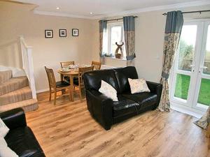 a living room with a black leather chair and a table at Breedsmoor Cottage in Ore