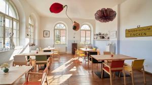 ein Restaurant mit Holztischen, Stühlen und Fenstern in der Unterkunft Kavaliershaus Schloß Blücher am Finckenersee in Fincken