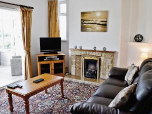 a living room with a couch and a fireplace at Grey Cottage in Pentraeth