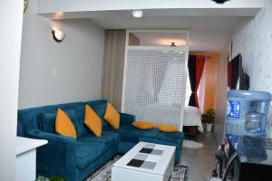 sala de estar con sofá azul y almohadas de color naranja en Tsavo Studio Lavish Home-307 en Nairobi