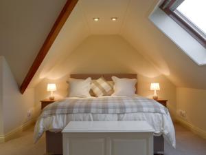 a attic bedroom with a bed with two lamps at Swallows Nest in Crich