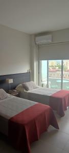 two beds in a room with a large window at Soles de Salta dpto, cochera, balcón a 600m de plaza principal in Salta
