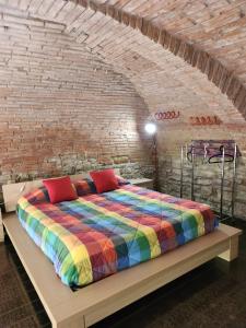 a bedroom with a colorful bed in a brick wall at Comfort Accommodation Loft in Bergamo
