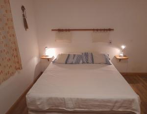 a bedroom with a white bed with two lights on it at Casa Naranja in Merlo