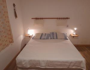 una camera da letto con un letto bianco con due luci sopra di Casa Naranja a Merlo