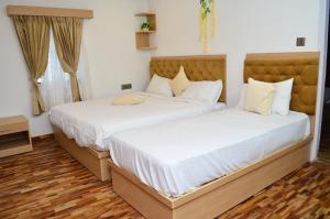 2 Betten in einem Zimmer mit weißen Wänden und Holzböden in der Unterkunft HILLINGTON COTTAGE in Kodaikanal