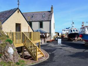 a house with a wooden ramp next to a boat at Rock Cottage in Saint Abbs