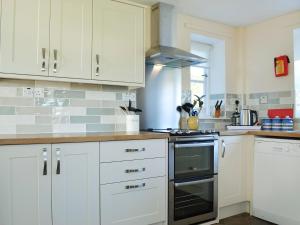 a kitchen with white cabinets and a stove top oven at Manor Cottage in Old Byland