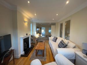 a living room with a white couch and a fireplace at Midsomer Cottage- Spacious Victorian Cottage with parking & garden - Close to City and ring road in Oxford