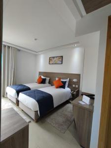 a bedroom with two beds with orange pillows at LOTUS HOTEL Casanearshore in Casablanca